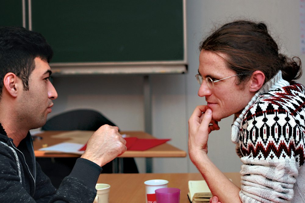 Ein Flüchtling und ein Pate unterhalten sich bei einem Kennenlerntreffen. Foto: Martin Reischke