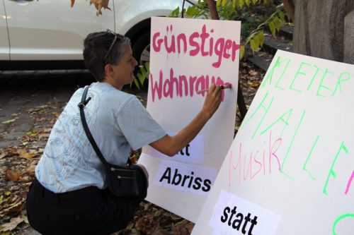 Eine Frau malt ein Plakat mit ihrem Nutzungswunsch für die ehemalige Schule. Foto: Hensel