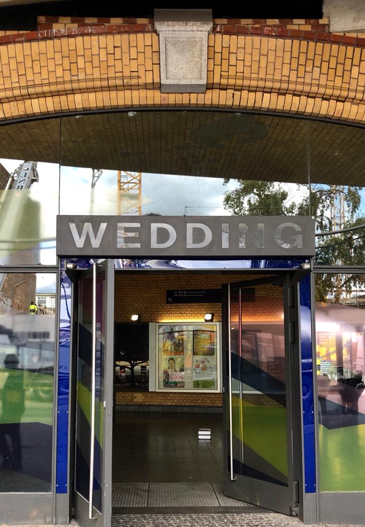EIne moderne Bahnhofstür und der Schriftzug Wedding