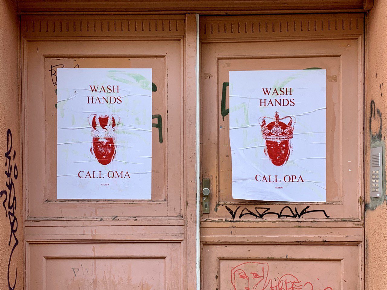 Zwei weiße Plakate auf einer rosa-orange farbigen Tür. Auf den Plakaten ist ein rotes Herz mit Krone zu sehen. Auf dem linken Plakat steht Wash Hands - Call Oma; auf dem rechten Plakat steht Wash Hands - Call Opa.