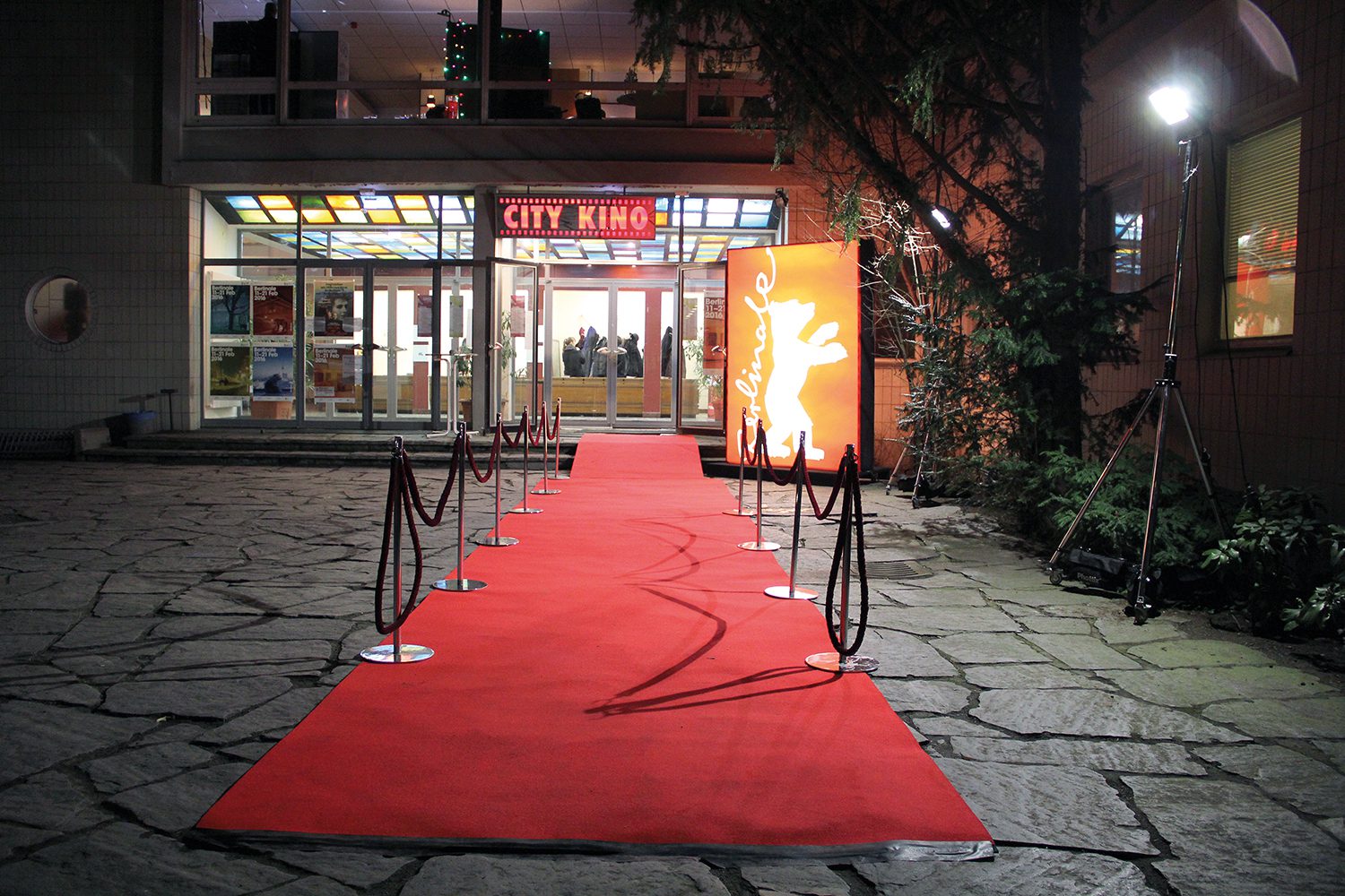 Ein Leuchtschild mit Berlinale-Bär und roter Teppich vor dem City Kino Wedding.