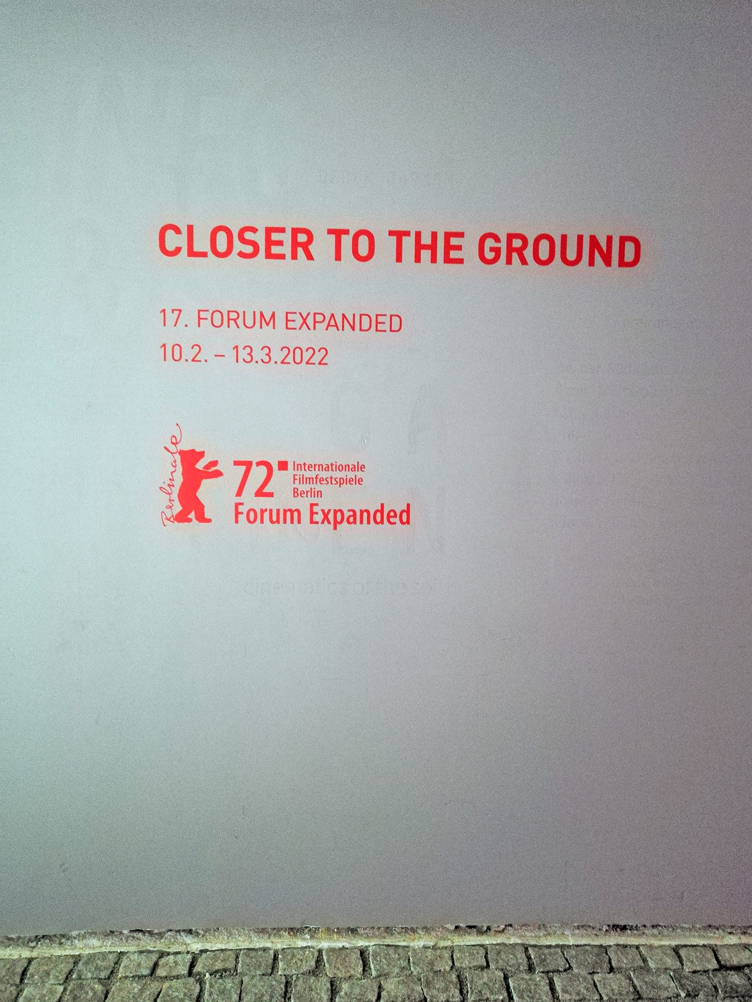 Schriftzug mit dem Ausstellungstitel "Closer to the Ground" an der Wand in der Betonhalle. Foto: Hensel