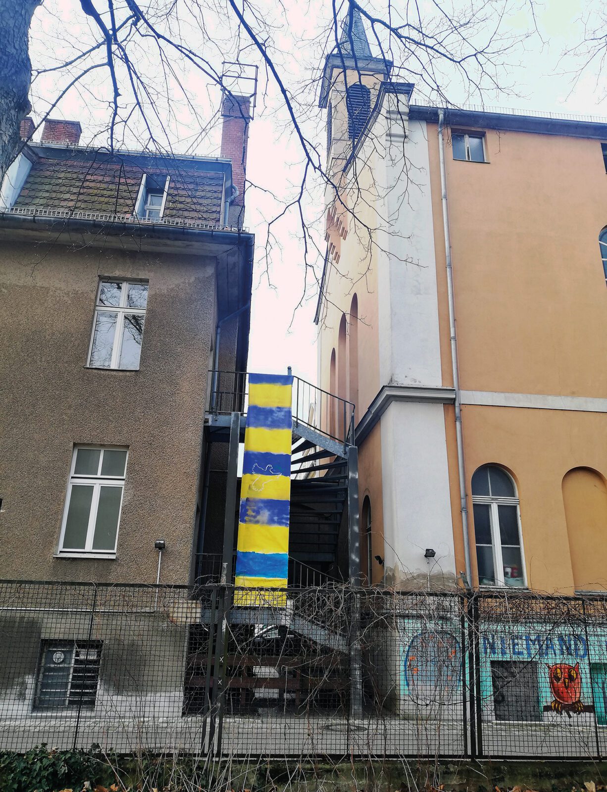Seit Anfang des Krieges hängt diese improvisierte Ukraine-Fahne am Eingang der Lazarus-Diakonie in der Bernauer Straße. An ihr vorbei geht es auch zur Spendenannahme. Foto: Hensel
