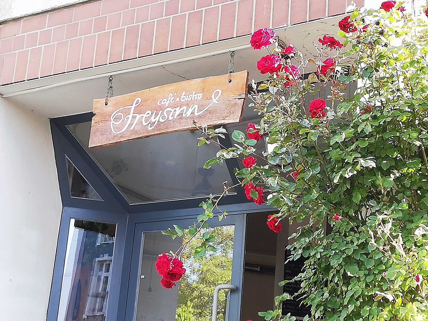 Café Freysinn, an der Eingangstür blühen die Rosen. Foto: Hensel