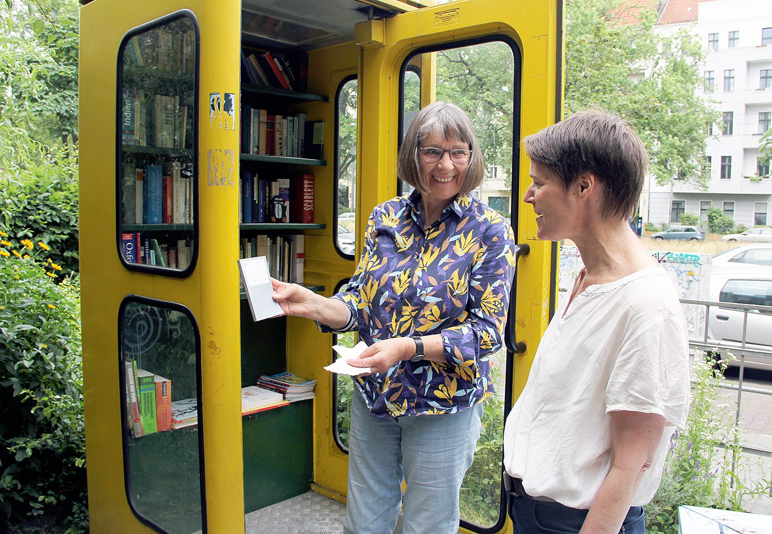 Cornelia zeigt Maike Janssen, was in der Bücherbox an der Fabrik Osloer Straße steht: das Grundgesetz. Foto: Hensel