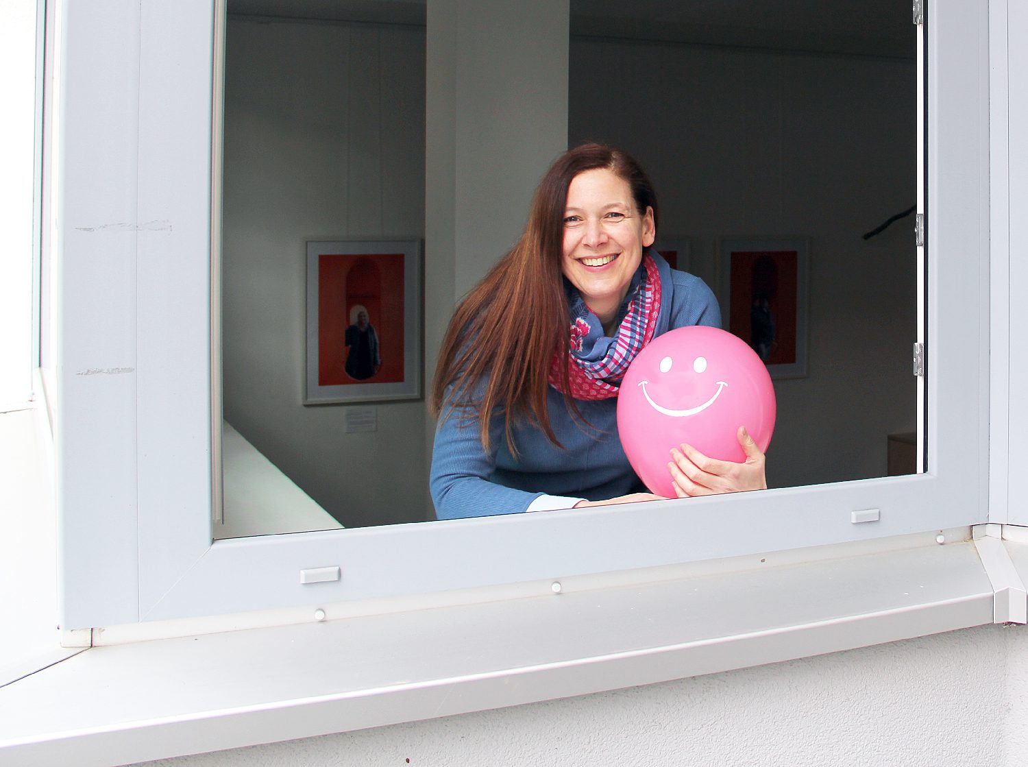 Stephanie Esser am offenen Fenster der Waschküche. Luftballons mit Smiley sollen den Kursteilnehmer:innen den Weg weisen. Foto: Hensel