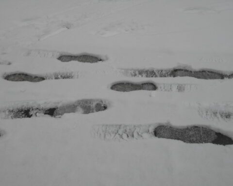 Sich begegnende Fußstapfen im nassen Schnee